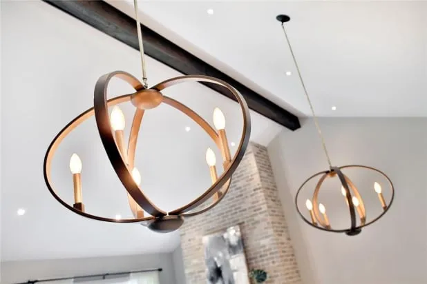 Two round metal pendant lights with candle-style bulbs, hanging beneath a dark beam on the vaulted ceiling.