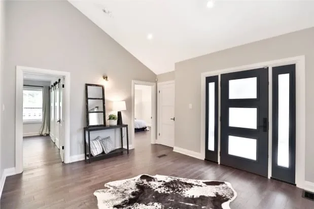 The finished entrance with a black front door and frosted sidelights, a console table and open doorways.